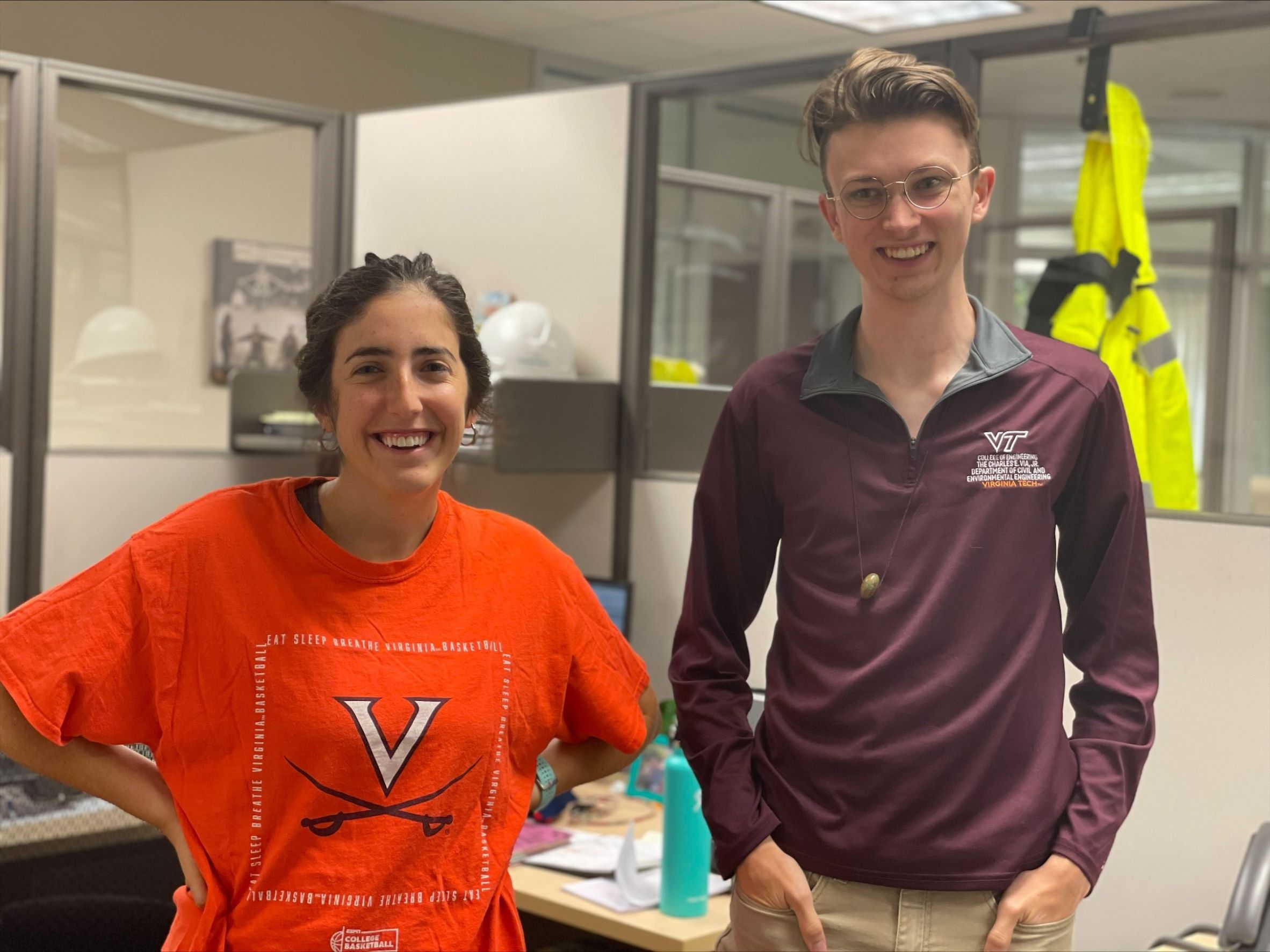 Leandra standing next to male coworker while both wear Virginia Tech clothes.