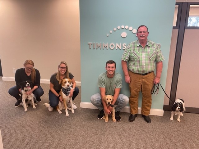 Four people from our Wilmington office posing with their dogs 