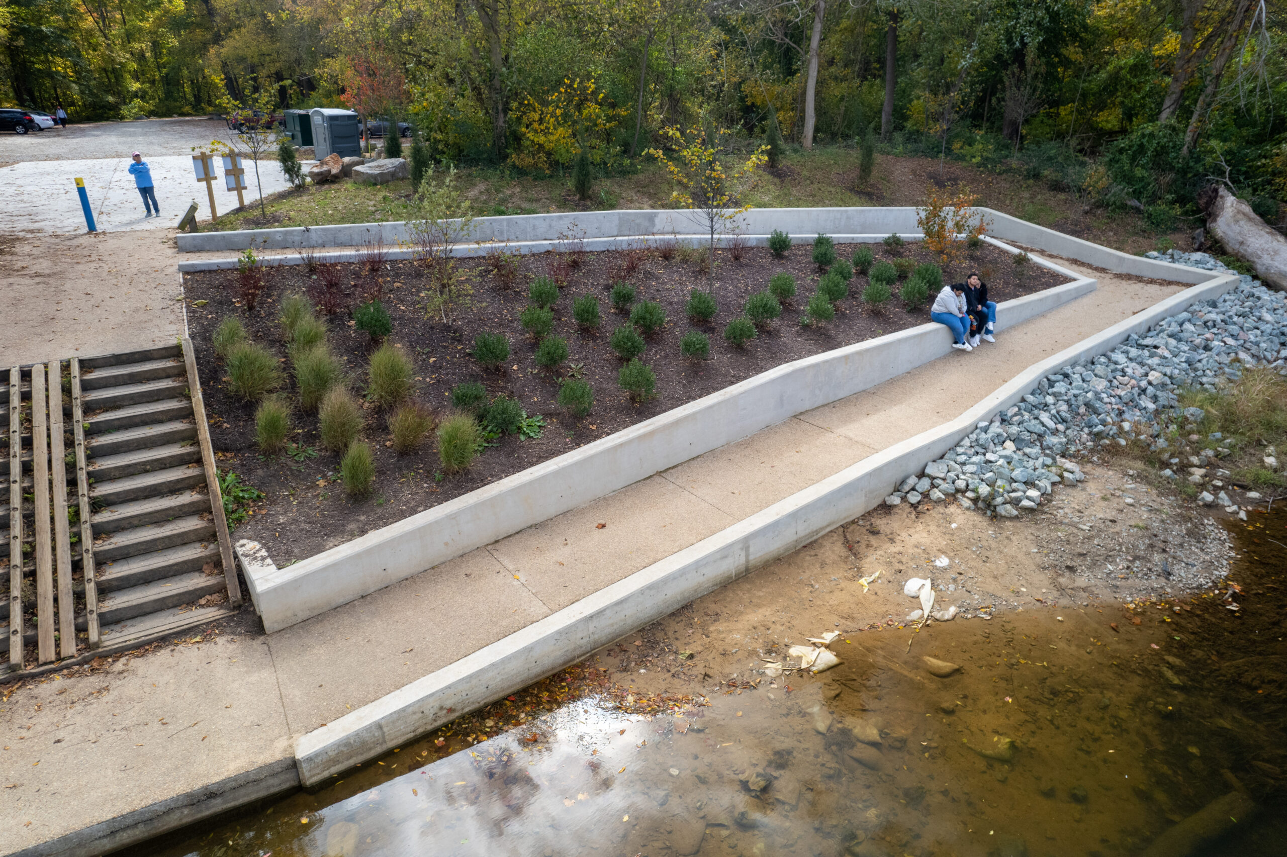 A closer look at the ramp shows it going in a square leading to the access point. In the middle of that square is greenery. Poeple are sitting on the ramp wall.