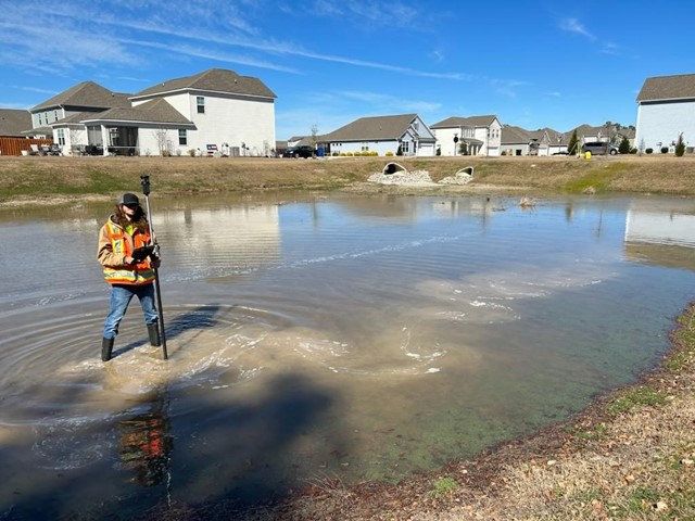 One of Ed's team members is seen standing in a bond with his waders on collecting data points.