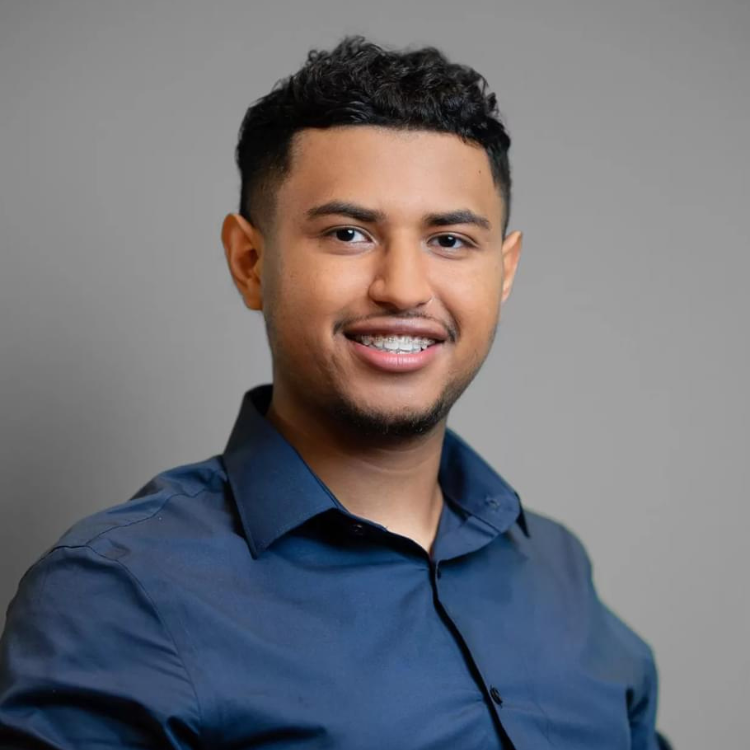 Headshot of Erik wearing a dark blue button down shirt against a grey background.