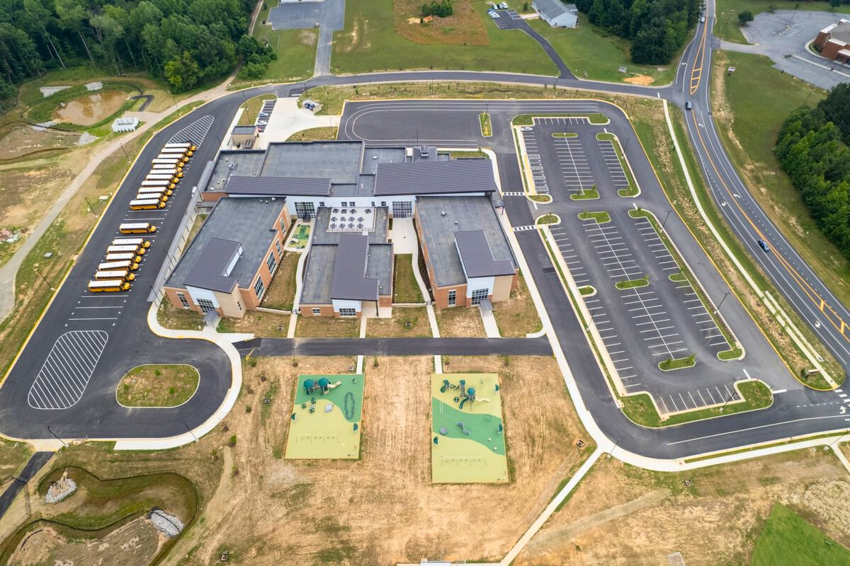 Above aerial view of Middle Road Elementary School, featuring the parking lot, bus loop, and outdoor playgrounds.