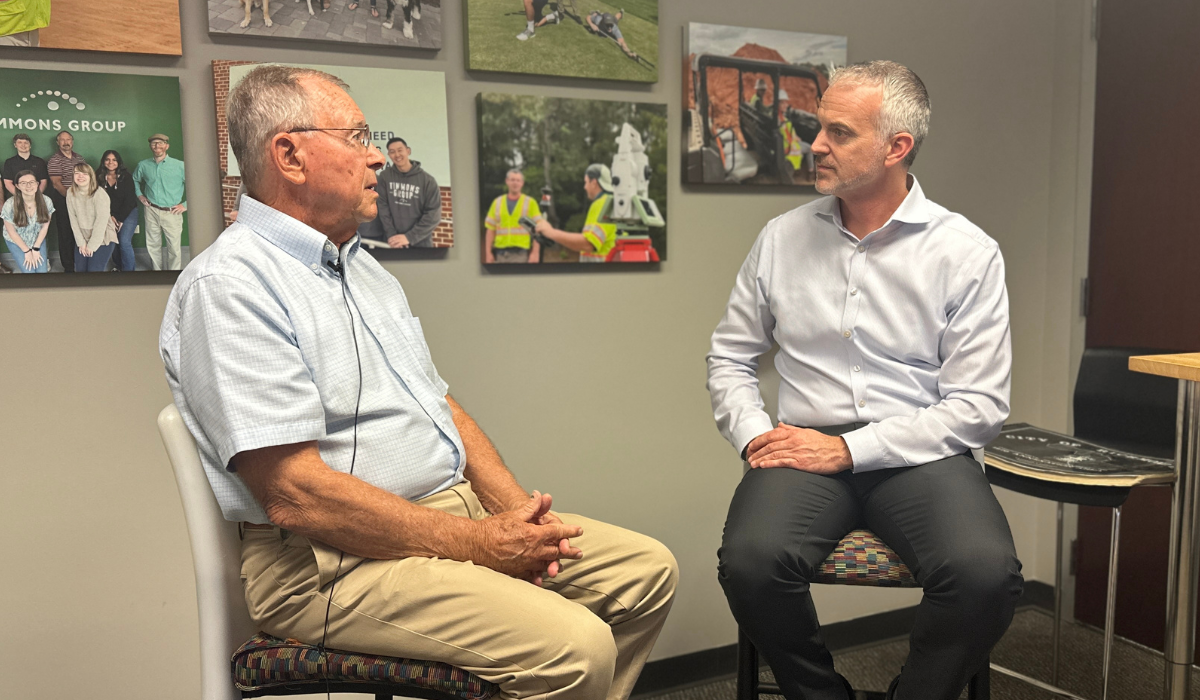 Jim Hayes sitting on the left and Tim Klabunde sitting on the right in front of a wall decorated with photo canvases.