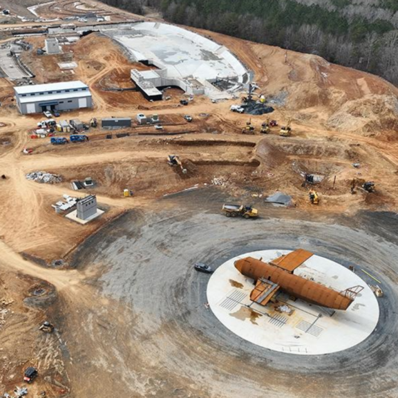 Aerial view of a construction site for a new highway, showcasing machinery, workers, and ongoing earth-moving activities.